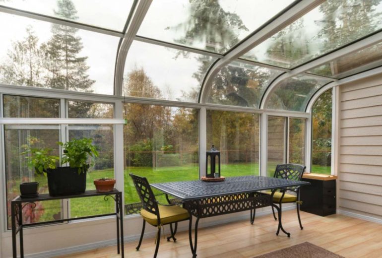 Classic sunroom with sloped glass roof and white-framed windows