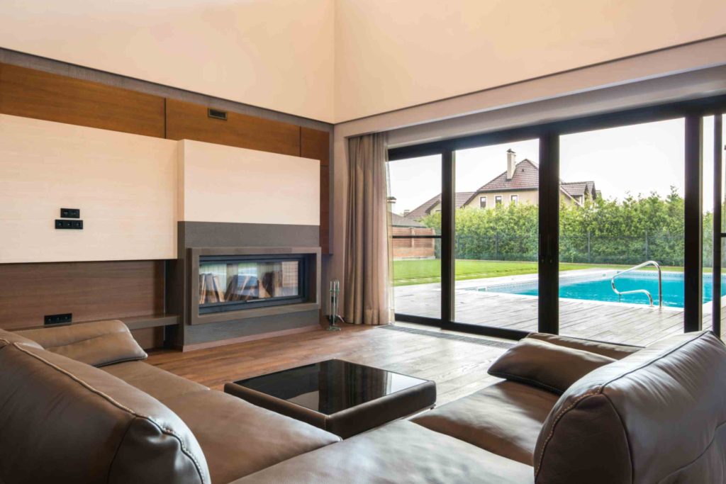 Living room with aluminium sliding doors facing a backyard pool and garden