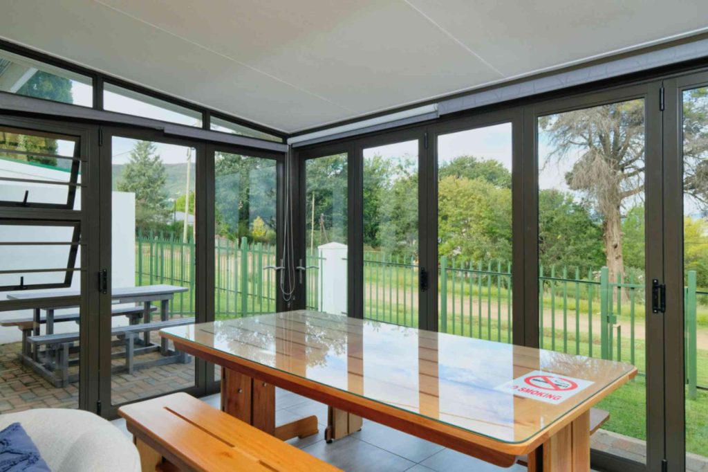 Sunroom dining area with aluminium folding glass doors and garden view
