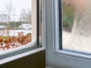 A close-up split image showing two different window issues: on the left, snow accumulation on a window sill with a view of a winter landscape; on the right, condensation heavily fogging a window pane.