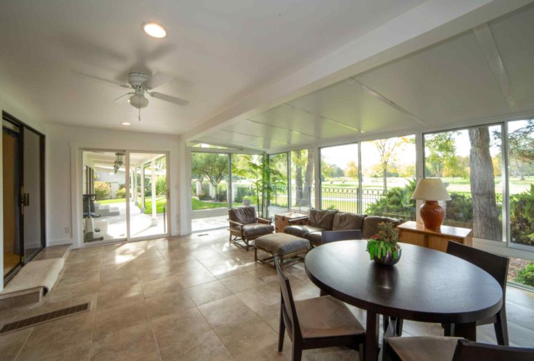 Bright modern sunroom with large windows, leather seating and garden view