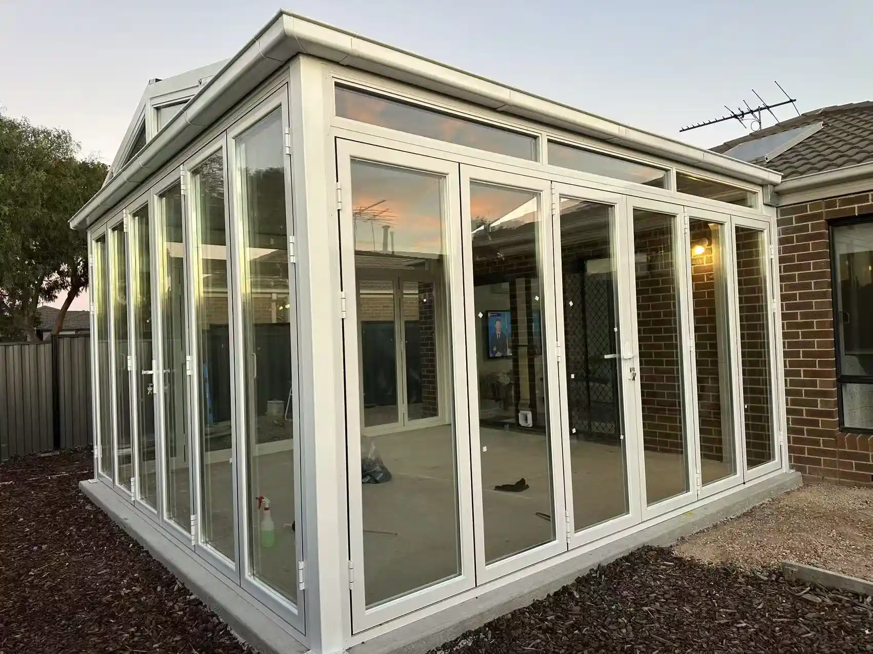Completed conservatory-style sunroom extension with white aluminium frames