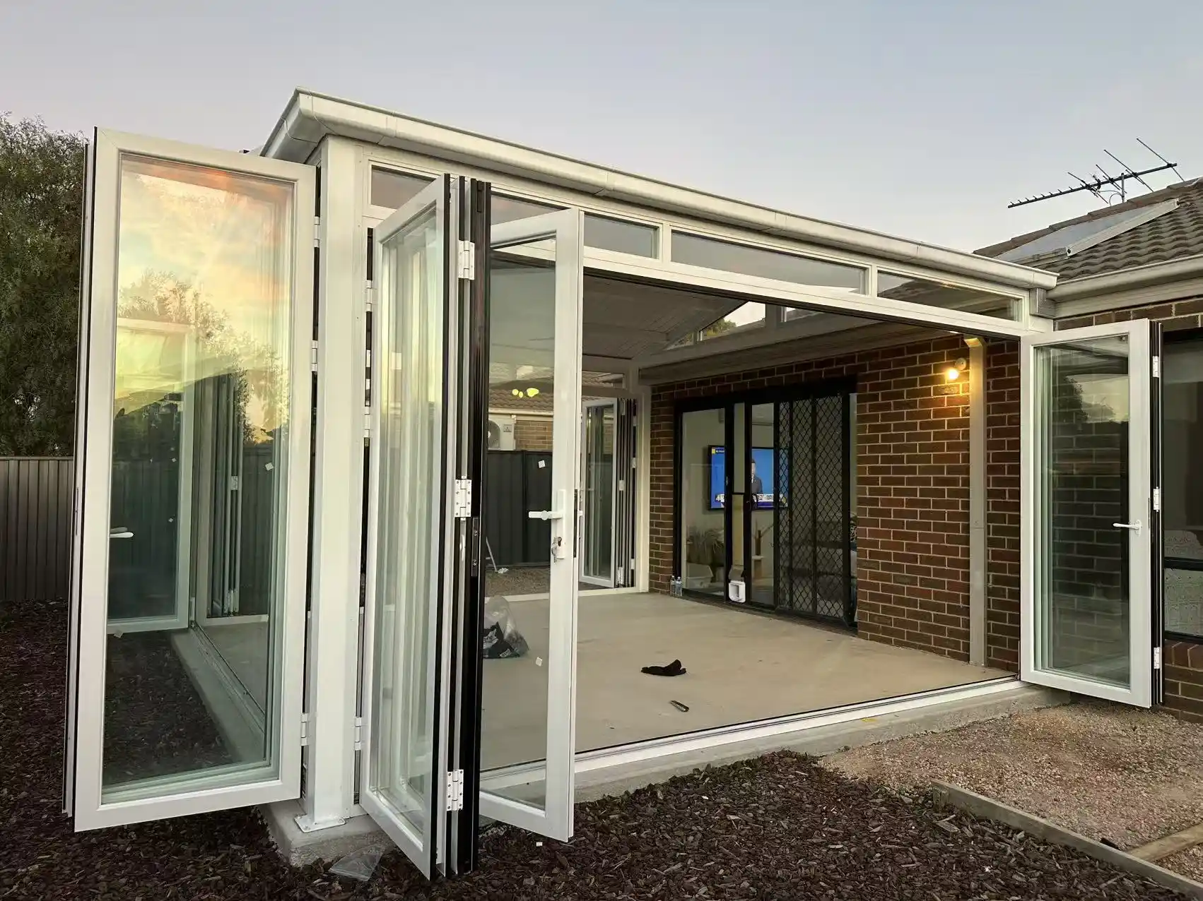 Sunroom extension against the original brick wall, bifold panels stacked to one side