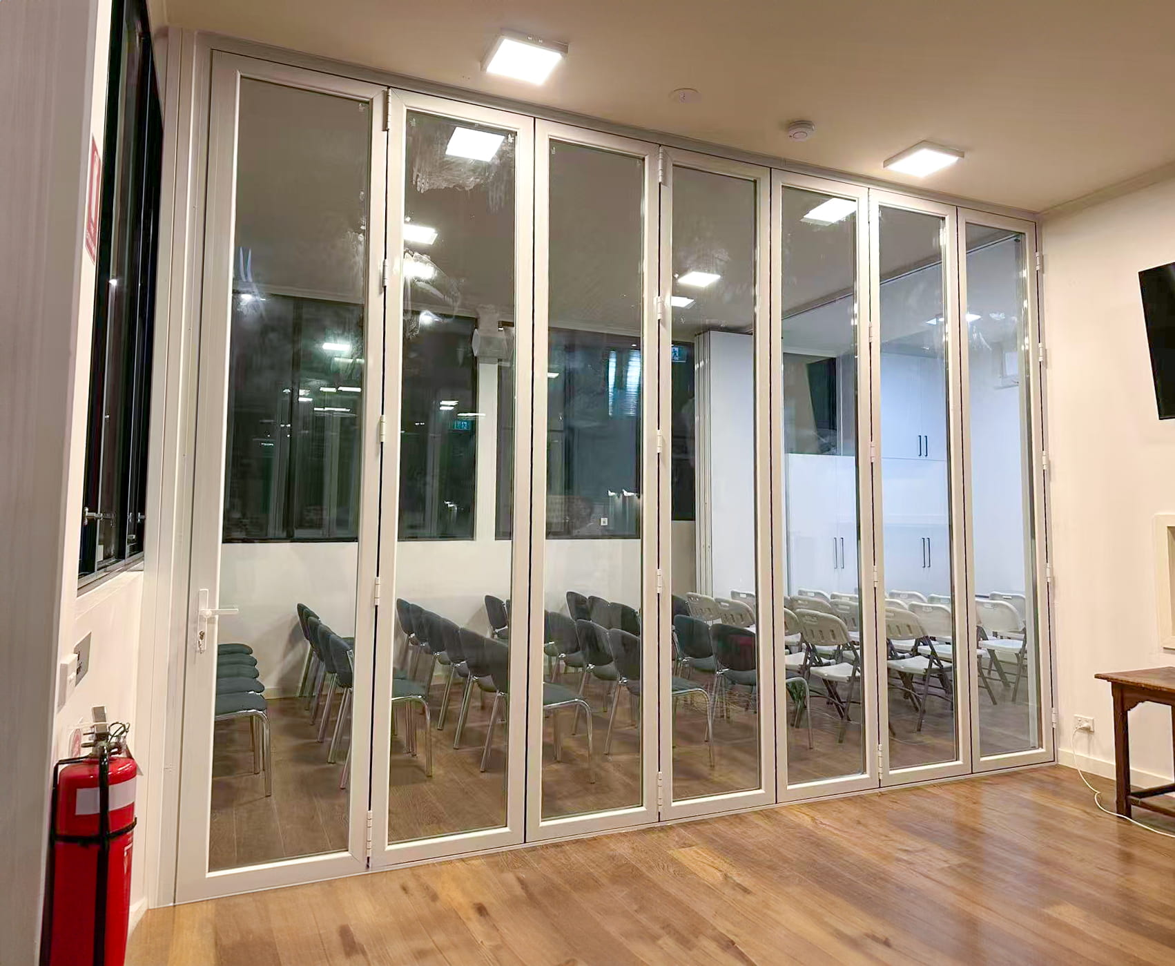 Floor-to-ceiling folding glass partition wall being fitted on its track